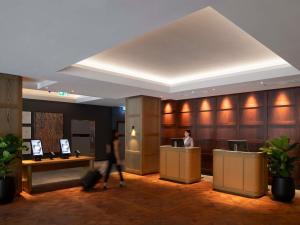 a lobby of a hotel with a man standing at a counter at Novotel Sydney City Centre in Sydney