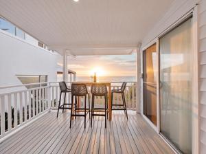 a table and chairs on a balcony with a view of the ocean at The Pink Door, Absolute Beachfront House in Scarborough