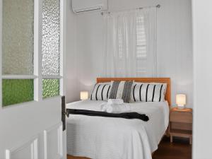 a white bedroom with a bed and a window at The Pink Door, Absolute Beachfront House in Scarborough
