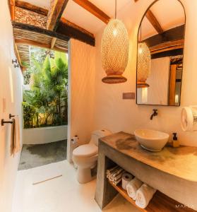 a bathroom with a sink and a toilet and a mirror at Ecohotel Raices del Rosario in Cartagena de Indias