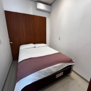 a small bedroom with a bed with a wooden door at Apartamento 2 Quartos centro da cidade in Parauapebas