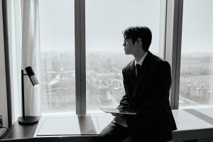 a man in a suit sitting in front of a window at Hotel Onoma Daejeon, Autograph Collection in Daejeon