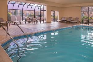 a pool in a hotel with chairs and tables at AmericInn by Wyndham Brookfield in Brookfield