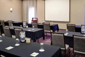 a conference room with tables and chairs and a screen at AmericInn by Wyndham Brookfield in Brookfield