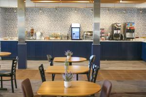 a restaurant with wooden tables and chairs and a counter at AmericInn by Wyndham Brookfield in Brookfield