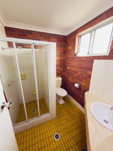 a bathroom with a shower and a toilet and a sink at Glen Innes Lodge Motel in Glen Innes +67 photos