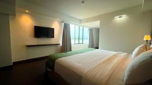 a hotel room with a bed and a television at Wiltop Hotel Jambi in Jambi