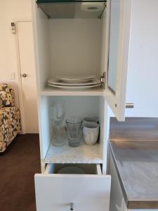 a white cabinet with some dishes in a kitchen at Tree of Love in Cambridge +20 photos