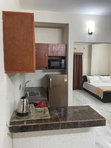 a kitchen with a sink and a refrigerator and a bed at Best Eastern Suite in Dhaka
