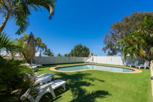 a swimming pool in a yard with chairs and trees at Jara - U19 Pandanus Palms Resort in Point Lookout