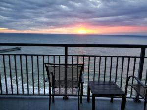 a chair and a table on a balcony with the ocean at Oceanfront Paradise Sleeps 10 w Stunning Sunrises in Myrtle Beach +210 photos
