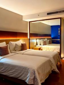 a hotel room with two beds and a mirror at Ra Premiere Simatupang in Jakarta