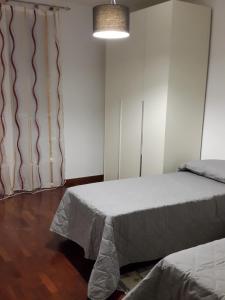 ネグラールにあるAppartamento Valparadisoのベッドルーム1室(ベッド2台付)、窓(カーテン付)