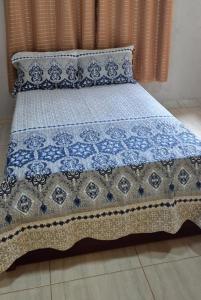 a bed with a blue and white quilt on it at Chalés Mirante da Lua Chalé 4 in Cavalcante