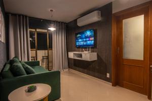 a living room with a green couch and a tv at Refúgio do poeta in Natal