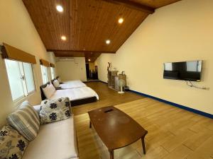a living room with a couch and a bed and a tv at 上好所在民宿 in Shoufeng