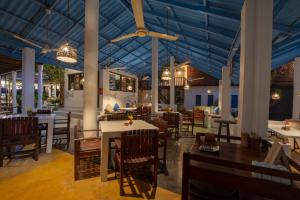 a restaurant with tables and chairs and a blue ceiling at Surf Resort Arugambay in Arugam Bay