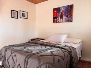 a bedroom with a bed with a painting on the wall at Casa de Helen in Antiguo Cuscatlán
