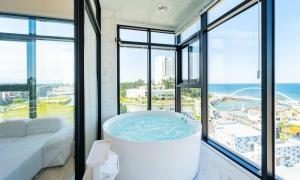 a large bath tub in a room with windows at Gangneung Skaria Poolvilla in Gangneung