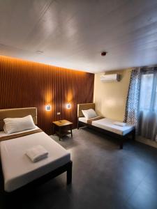 a hotel room with two beds and a window at Claytown Pension House in Dumaguete