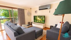 a living room with two couches and a flat screen tv at Wemberley Lakehouse in Wangi Wangi