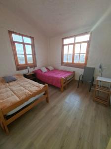 a bedroom with two beds and a desk and two windows at Villa Luna in Chincha +6 photos