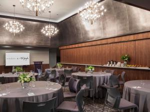 a dining room with tables and chairs and chandeliers at Ändra Hotel Seattle - MGallery Collection in Seattle