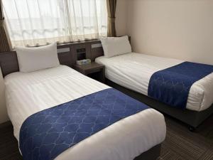 a hotel room with two beds with blue and white sheets at Airport Plaza Hotel in Tomisato