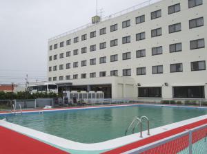 a swimming pool in front of a building at Airport Plaza Hotel in Tomisato
