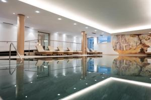 a house with a swimming pool with chairs and a swimming pool at Sporthotel Floralpina in Alpe di Siusi