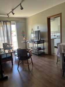 a living room with chairs and a table and a television at Conforto e simplicidade no centro da cidade in Santana do Livramento