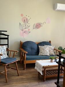 a living room with a blue couch and flowers on the wall at Conforto e simplicidade no centro da cidade in Santana do Livramento
