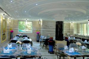 a dining room with tables and chairs and a ceiling at Fountain Palace Hotel & Suites in Kampala