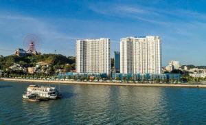 a boat in the water near a city with tall buildings at Sapphia Hạ Long in Ha Long