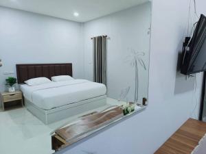 a bedroom with a bed and a tv and a mirror at สวนไผ่รีสอร์ท in Ban Na