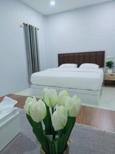a bedroom with a bed and a vase with white flowers at สวนไผ่รีสอร์ท in Ban Na