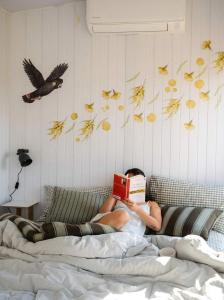 a man laying on a bed reading a book at Gem near the Dam by Tiny Away in Romsey