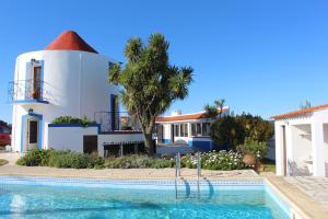 a villa with a swimming pool in front of a house at Windmill Hill in Cercal