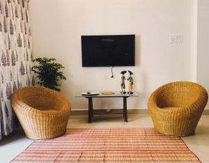 a living room with two chairs and a table with a tv at Parijat Heritage in Bhubaneshwar
