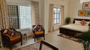 a bedroom with a bed and two chairs and windows at Parijat Heritage in Bhubaneshwar