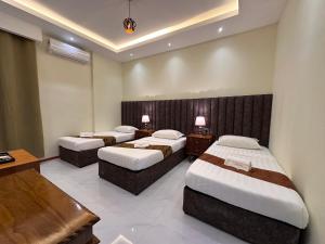 a hotel room with three beds and a desk at Grand Luxury Hotel Semporna in Semporna