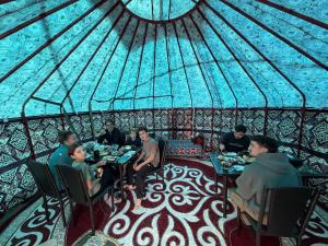 a group of people sitting at tables in a yurt at Kochmon guesthouse in Naryn +66 photos