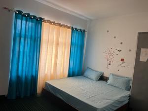 a bedroom with a bed with blue drapes at Bittu Homestay in Kaza
