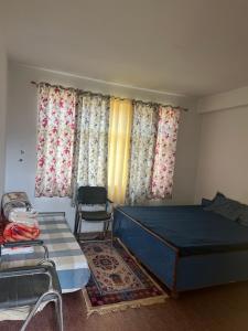 a bedroom with a bed and a chair and curtains at Bittu Homestay in Kaza
