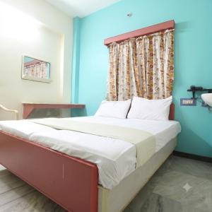 a bed in a room with a blue wall at Sri Ganapathy Lodge in Coimbatore