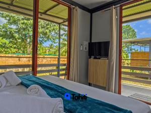 a bedroom with a bed and a balcony with a tv at Tekehani Lodge in Araito