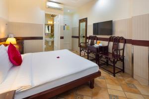 a bedroom with a bed and a desk and a television at Pink Horizon Saigon Airport Hotel in Ho Chi Minh City