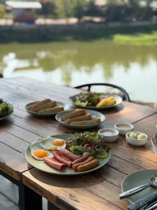 a wooden table with plates of food on it at Glai boutique hotel in Ban Cha Prong