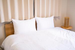 a white bed with white sheets and pillows at Umibe no yado yo-riyo-ri in Amami