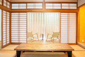 a room with two chairs and a wooden table at Umibe no yado yo-riyo-ri in Amami